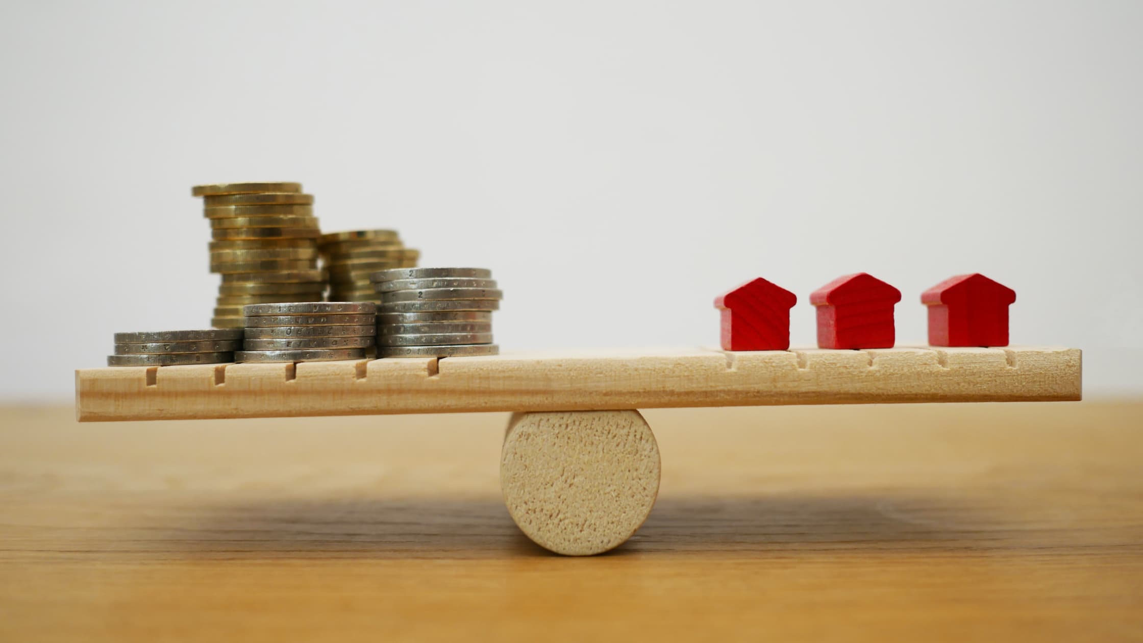 Stacked coins balancing with miniature houses representing average closing costs in Colorado real estate