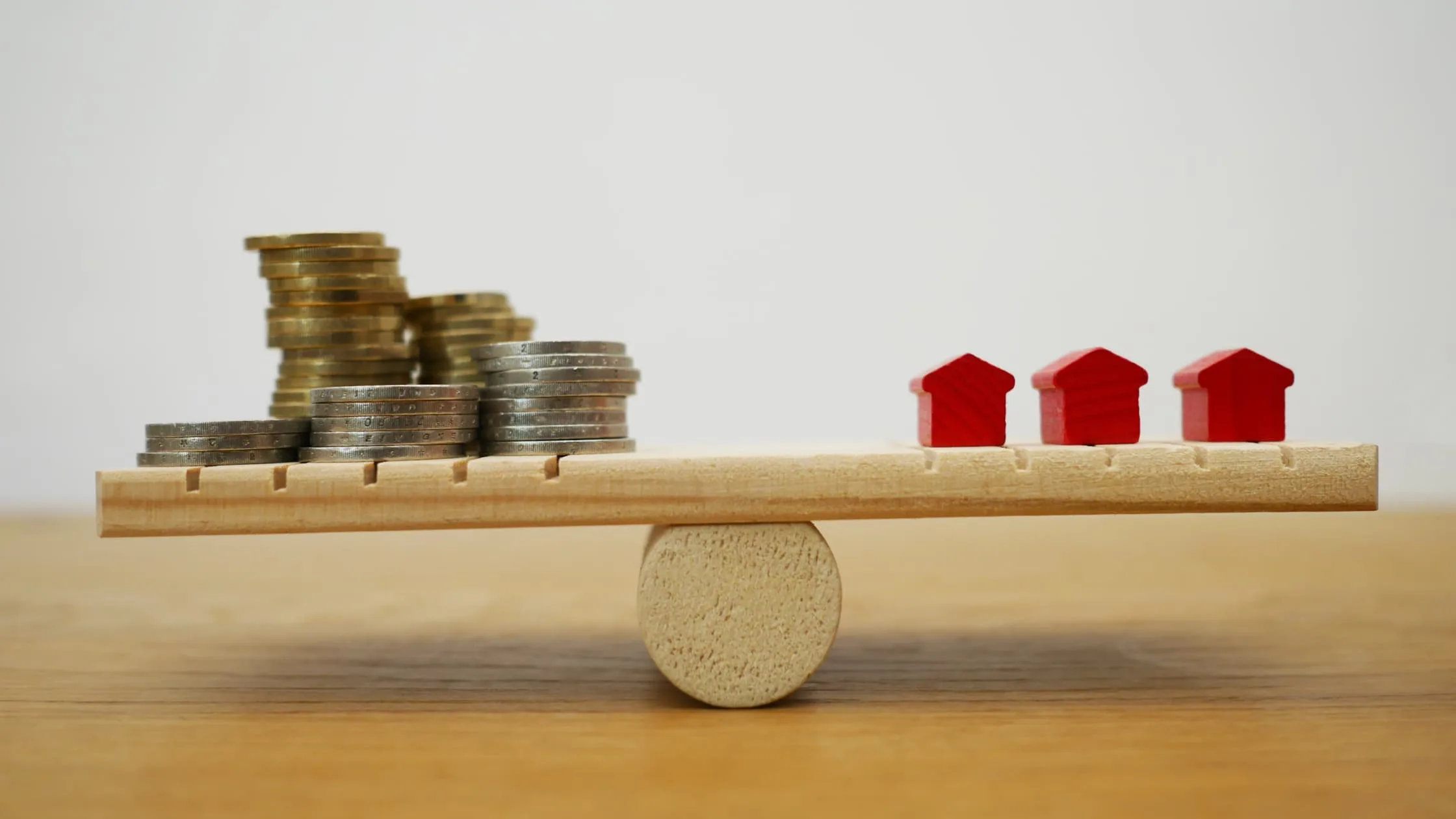 Stacked coins balancing with miniature houses representing average closing costs in Colorado real estate