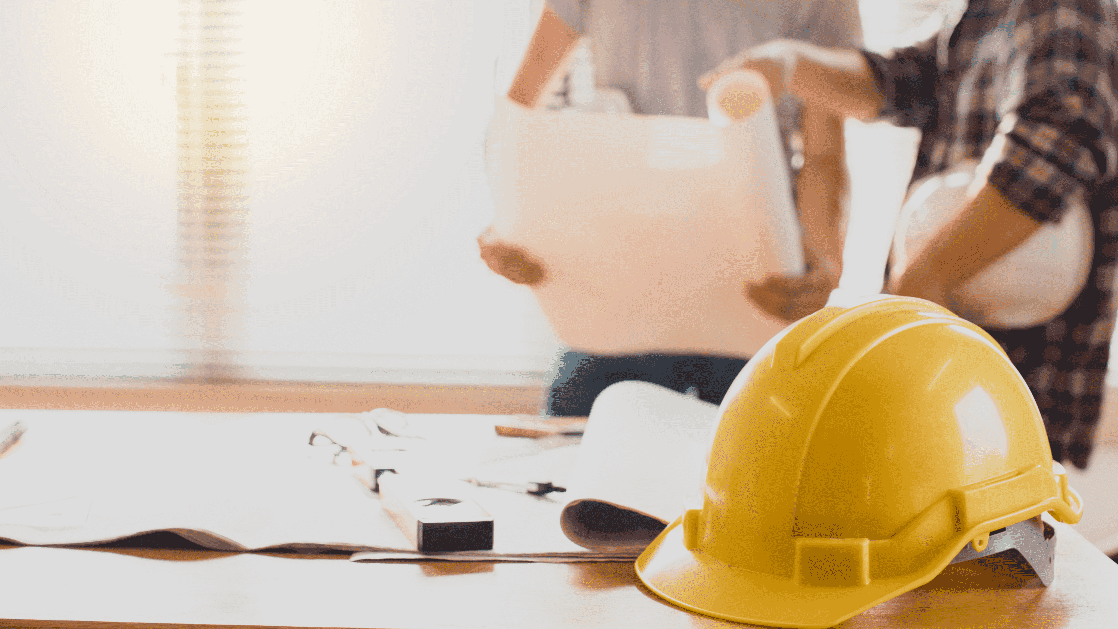 Yellow hard hat and blueprints on a desk for ADU construction in Denver.