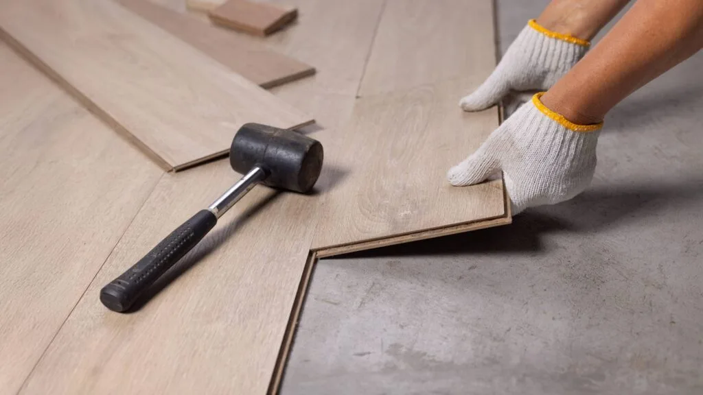 Close up of flooring installation during a home renovation Denver project, showing planks being aligned and secured.