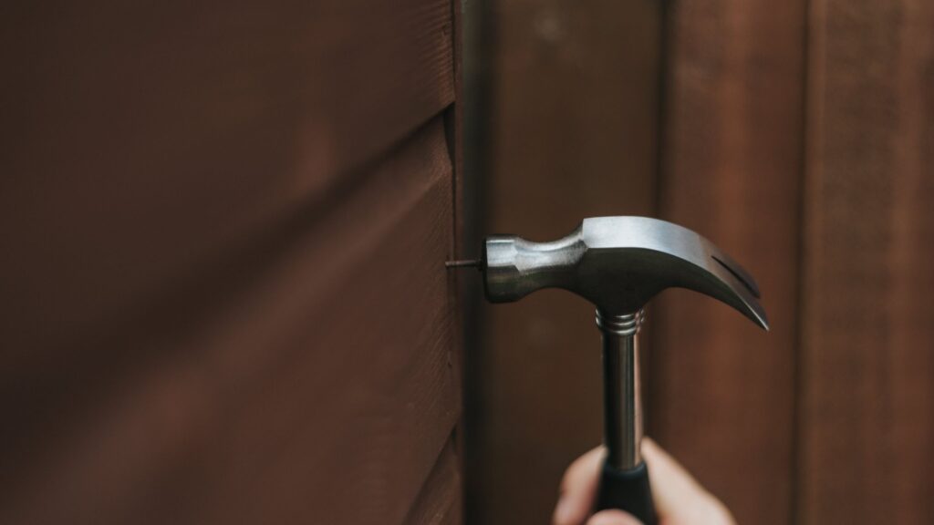 Hammer on wood surface illustrating what not to fix when selling a house to avoid unnecessary repairs