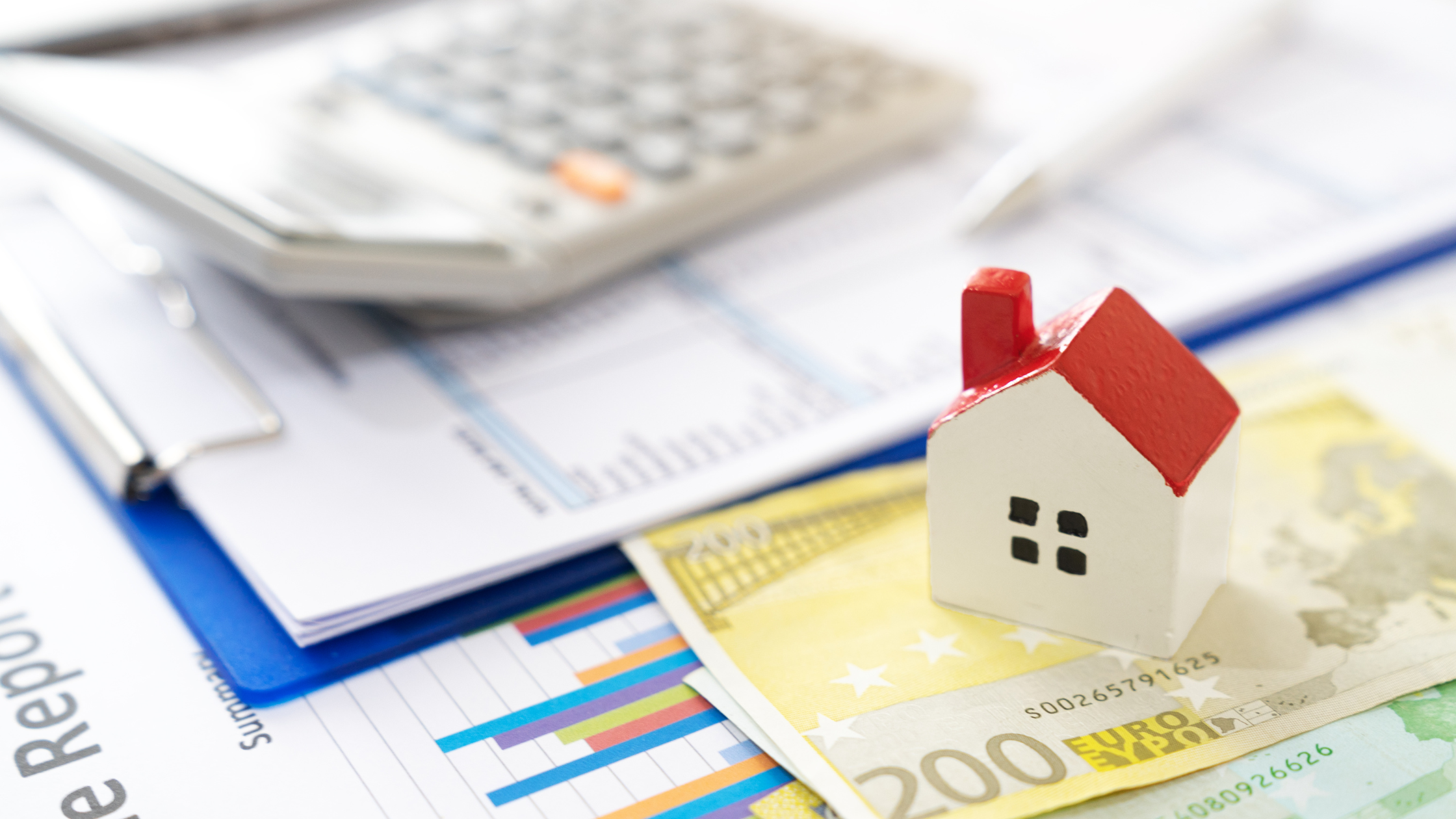 House model on financial documents and calculator illustrating title insurance Colorado costs and closing expenses.