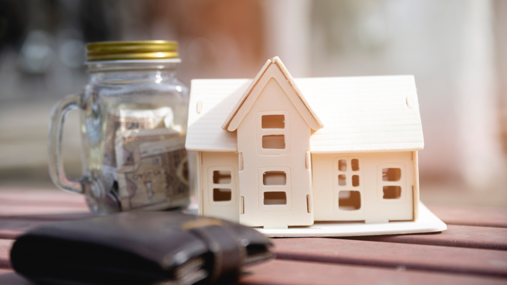Wooden home model beside savings jar symbolizing long-term protection through title insurance Colorado.
